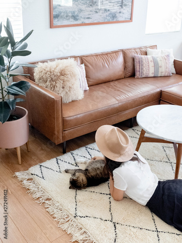 Young woman laying on living room rug with cat photo