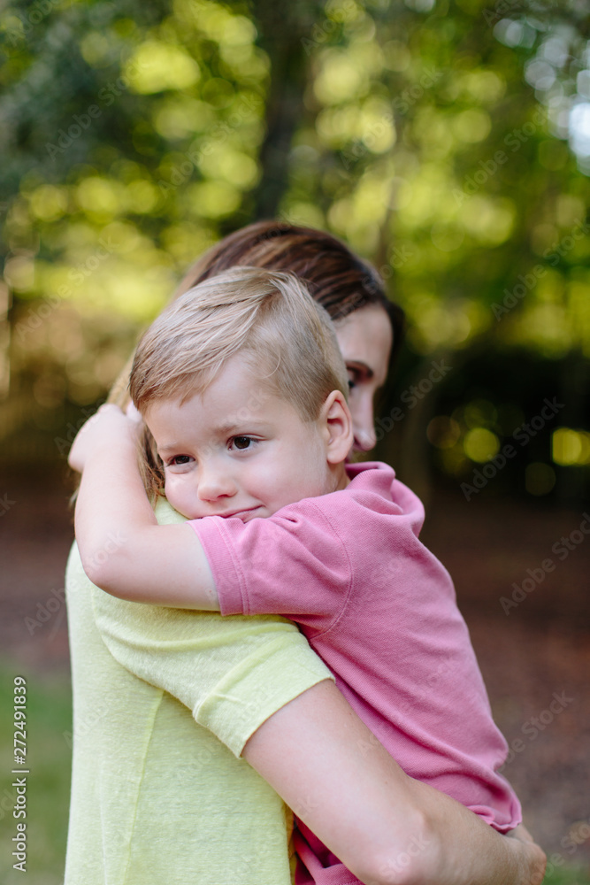 Cute young boy resting on his mother's shoulder Cute young boy resting on his mother's shoulder
