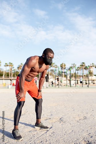 Portrait of muscular athlete in mask having a rest after trainin photo