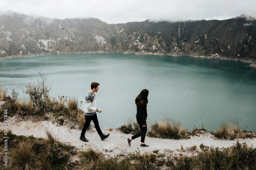 Two people walking across trail with a beautiful Two people walking across trail with a beautiful
