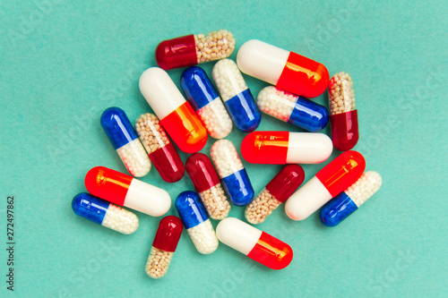 capsules (pills) on a turquoise background. Medical background, template.