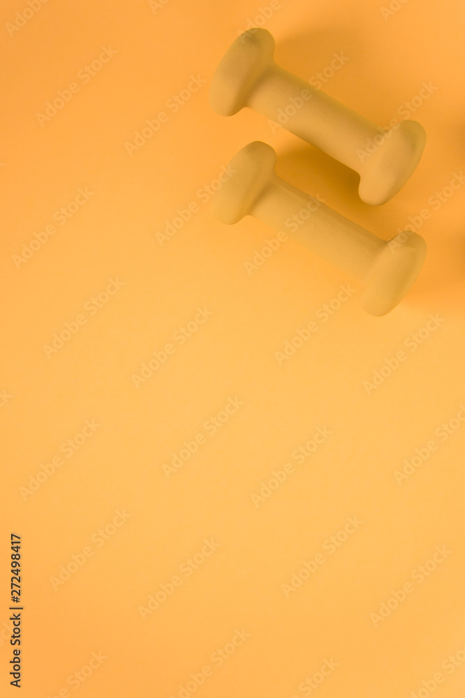 Fitness equipment with womens yellow weights/ dumbbells isolated on a yellow background with copyspace - obrazy, fototapety, plakaty 
