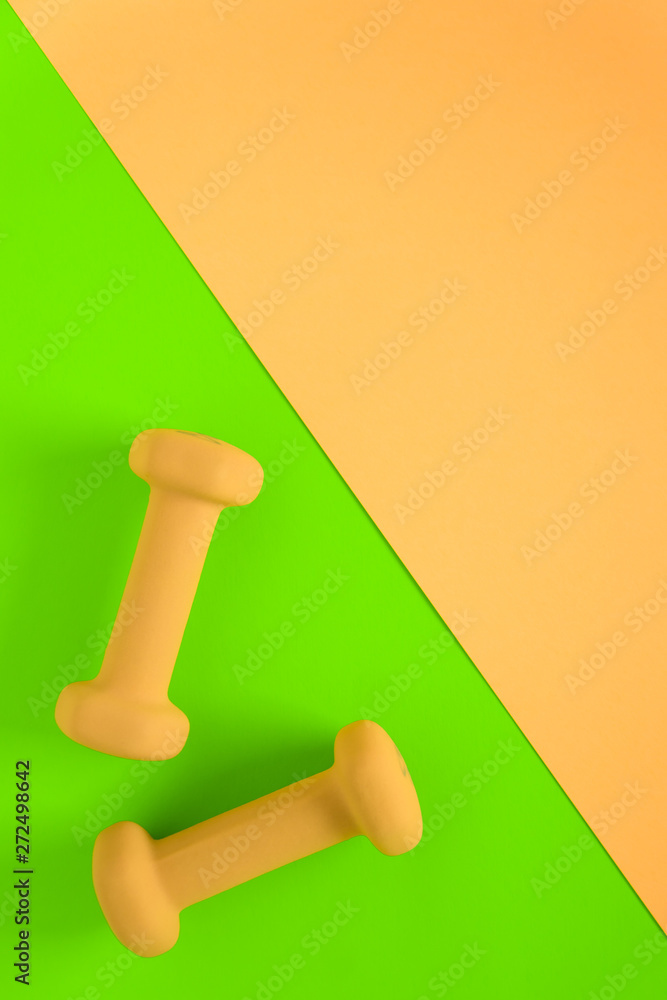 Fitness equipment with womens yellow weights/ dumbbells isolated on a lime green and yellow pink background with copyspace Fitness equipment with womens yellow weights/ dumbbells isolated on a lime green and yellow pink background with copyspace
