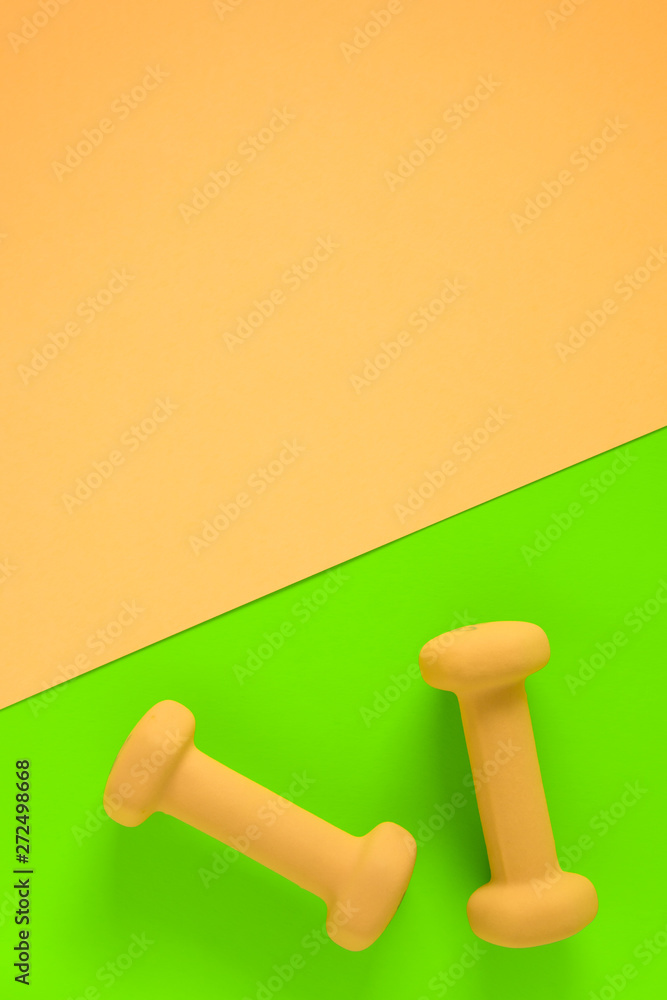 Fitness equipment with womens yellow weights/ dumbbells isolated on a lime green and yellow pink background with copyspace Fitness equipment with womens yellow weights/ dumbbells isolated on a lime green and yellow pink background with copyspace