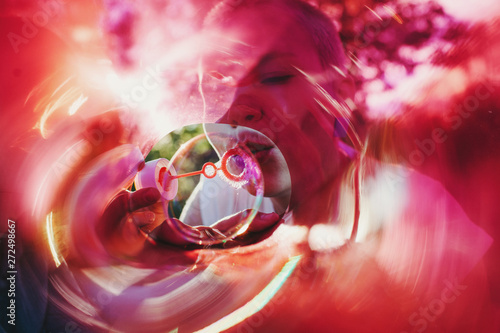 Woman blowing bubbles through light filter