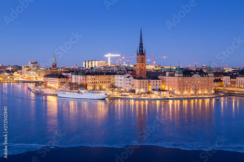 Riddarholmen - part of the historical Old Town (Gamla Stan) in Stockholm, Sweden, at dusk, in winter, surrounded by ice.