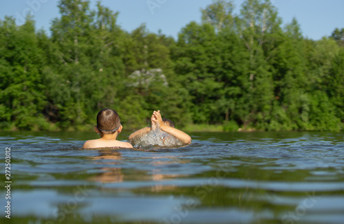 two teenage boys swim in the lake