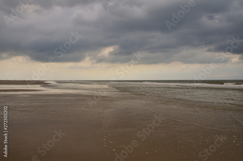 Fototapeta Naklejka Na Ścianę i Meble -  Plażą nad morzem w pochmurny dzień pod niebem z chmurami.