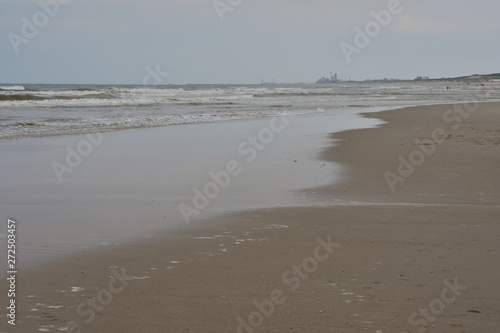 Plażą nad morzem w pochmurny dzień pod niebem z chmurami.