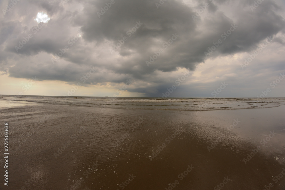 Plażą nad morzem w pochmurny dzień pod niebem z chmurami. Plażą nad morzem w pochmurny dzień pod niebem z chmurami.