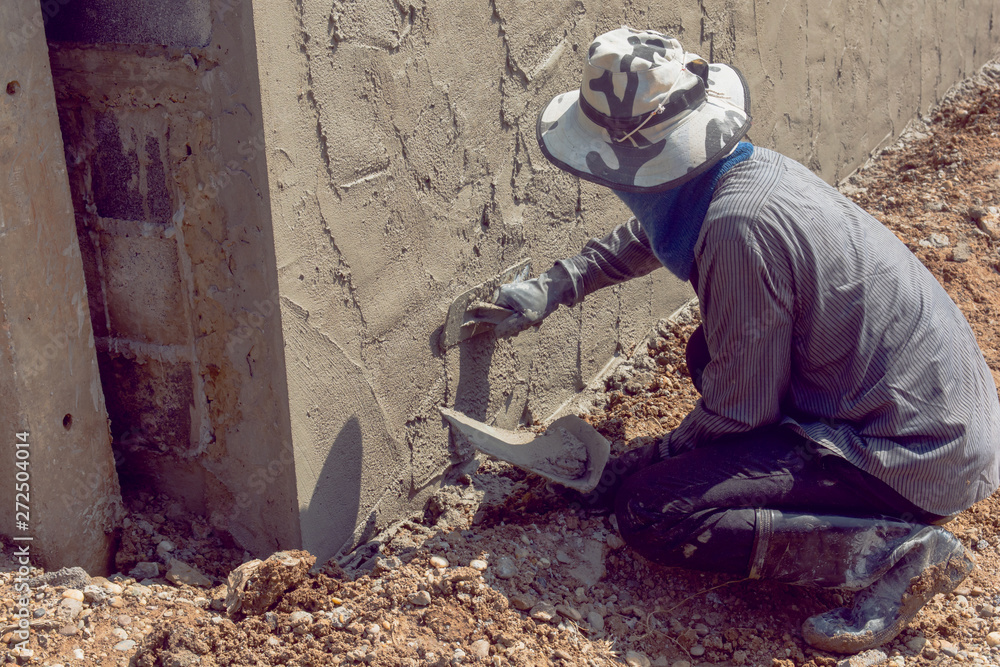 Obraz premium Construction workers plastering building wall using cement plaster