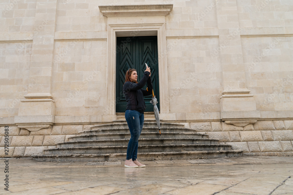 Young woman tourist photographs on an old city