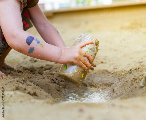Kind spielt mit Matsch auf Spielplatz. Child playing in the mud on playgroud. photo