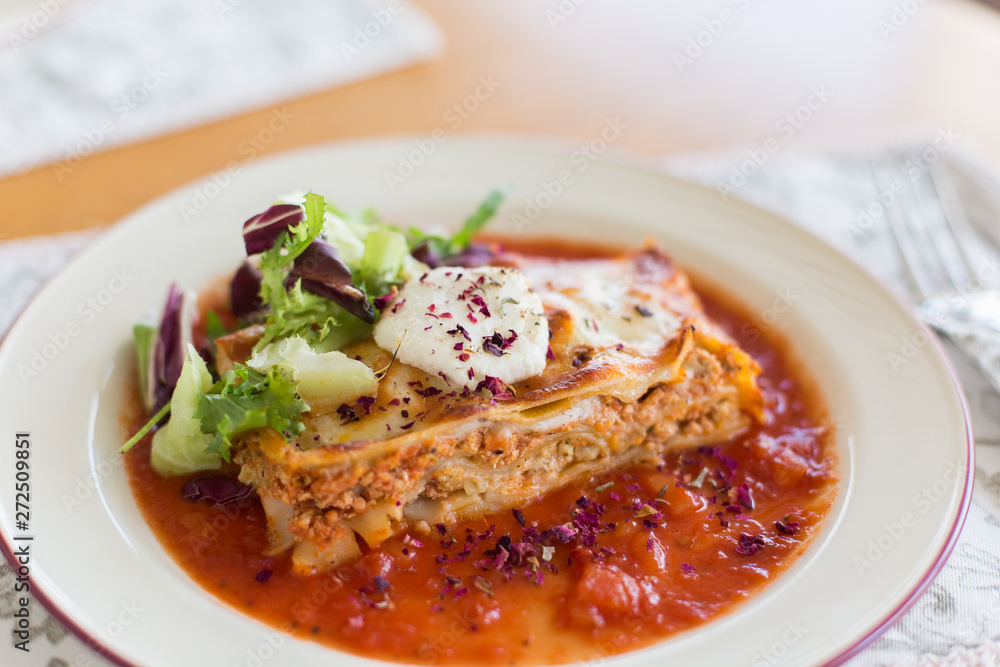 Tasty delicious italian dish lasagna with tomato sauce and cream cheese with green salat. Food, tasty dinner concept