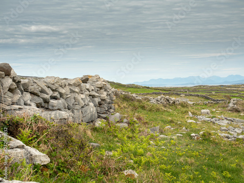 Traditional dry stone fence, Inishmore Aran Islands, Connemara mountain peaks in the background. Ireland.
