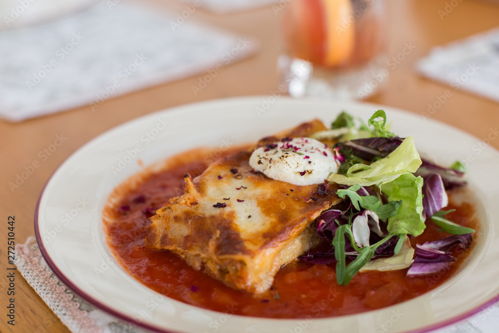 Tasty delicious italian dish lasagna with tomato sauce and cream cheese with green salat. Food, tasty dinner concept Tasty delicious italian dish lasagna with tomato sauce and cream cheese with green salat. Food, tasty dinner concept
