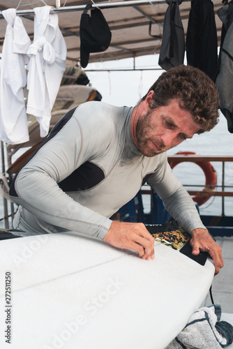 Surfer waxing surfboard