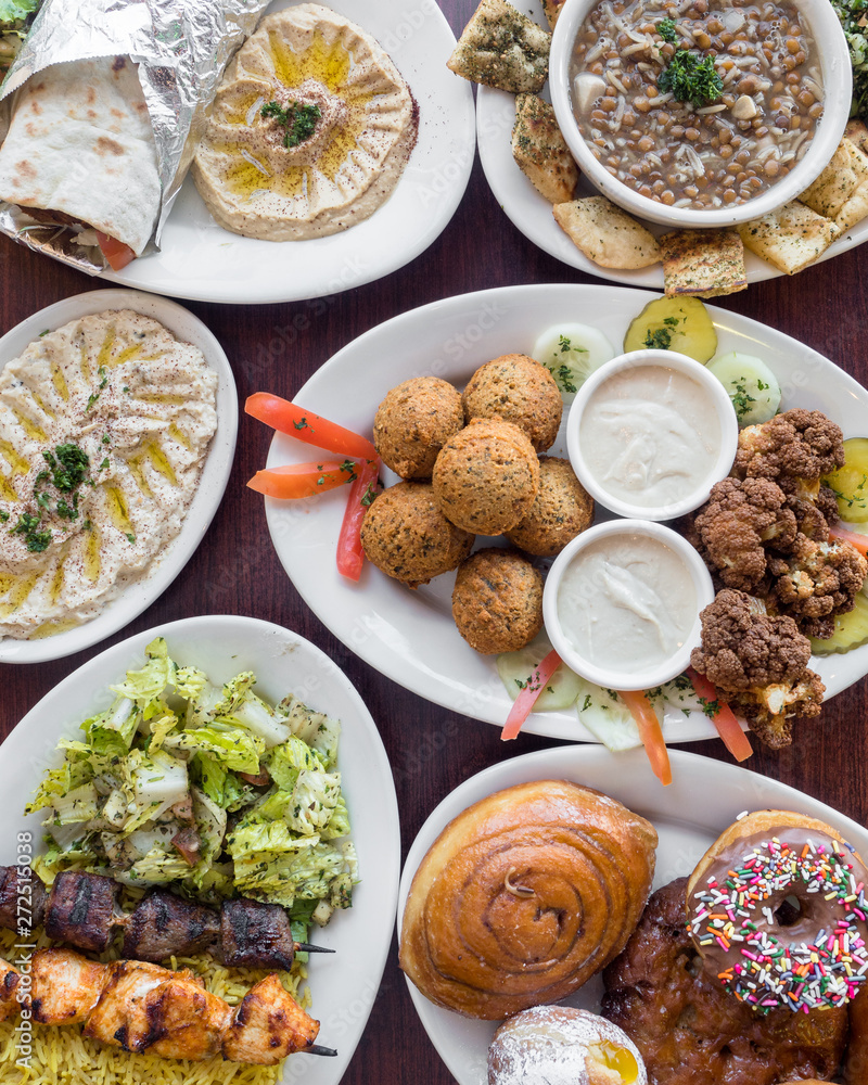 Falafel gyro, hummus, lamb, beef and chicken skewers, served with rice, hummus, and tzatziki sauce in a Greek restaurant. Falafel gyro, hummus, lamb, beef and chicken skewers, served with rice, hummus, and tzatziki sauce in a Greek restaurant.
