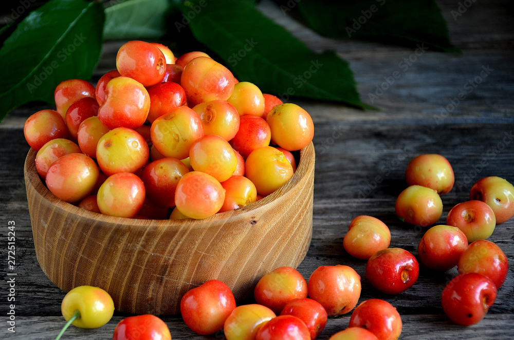 Sweet cherry in a wooden bowl on a wooden table. Sweet cherry in a wooden bowl on a wooden table.