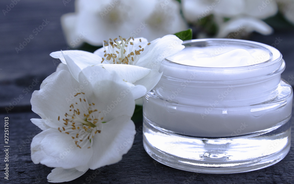 Cosmetic cream in a glass jar with jasmine flowers on a wooden background. Cosmetic cream in a glass jar with jasmine flowers on a wooden background.