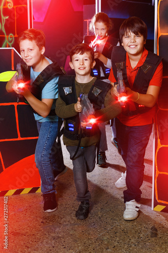 Group of happy teenagers with laser guns having fun on dark lase photo