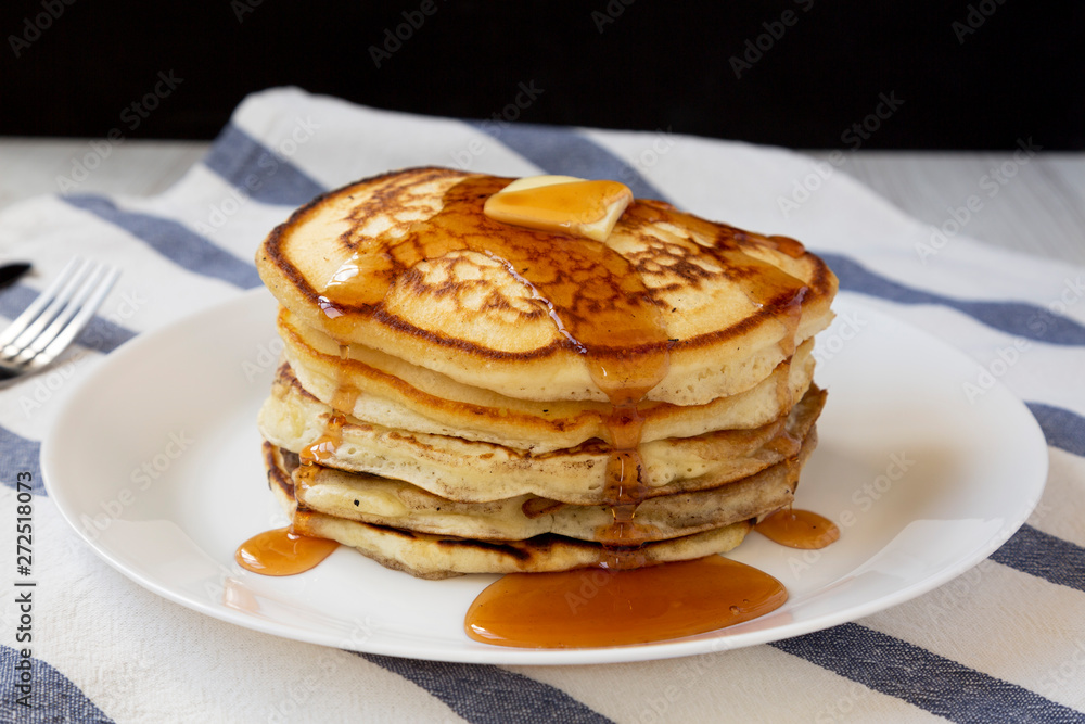 Homemade pancakes with butter and maple syrup on a white plate, side view. Close-up. Homemade pancakes with butter and maple syrup on a white plate, side view. Close-up.