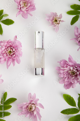 Pastel pink cosmetic product setting flat lay with flowers on white desk background, top view, frame. Layout for skin care, wellness or spa and beauty concept