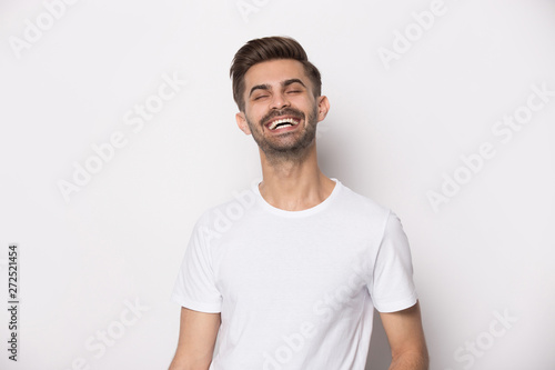 Laughing guy wearing white t-shirt posing on studio background © fizkes