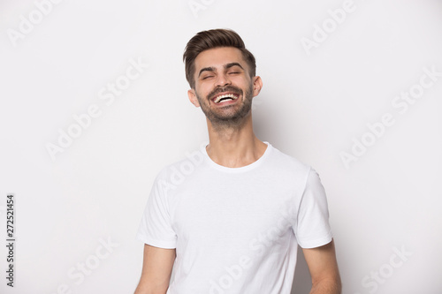 Laughing guy wearing white t-shirt posing on studio background