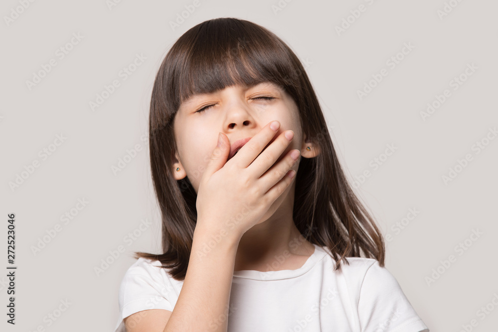 Little girl yawning feels sleepy isolated on beige studio background Little girl yawning feels sleepy isolated on beige studio background