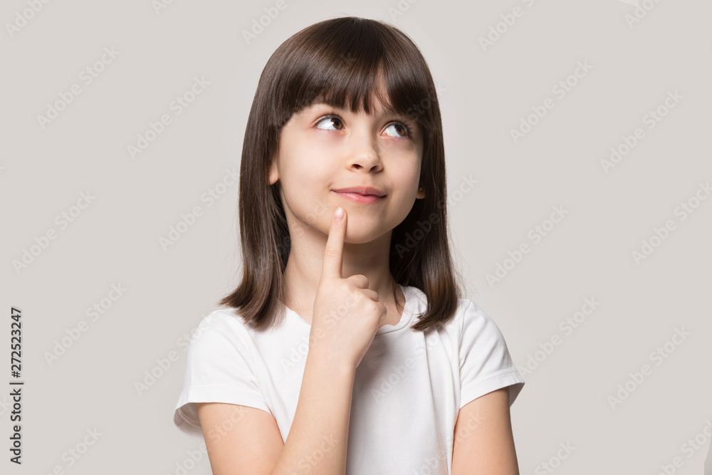 Pensive little girl hold finger on chin isolated on beige Pensive little girl hold finger on chin isolated on beige