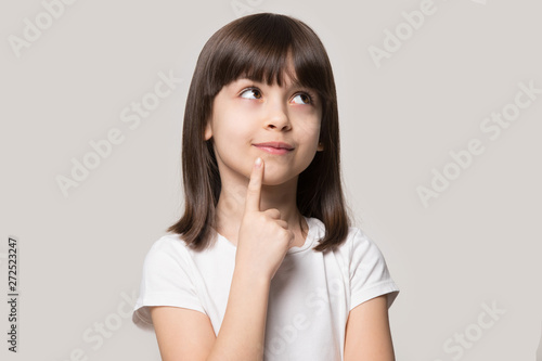 Pensive little girl hold finger on chin isolated on beige