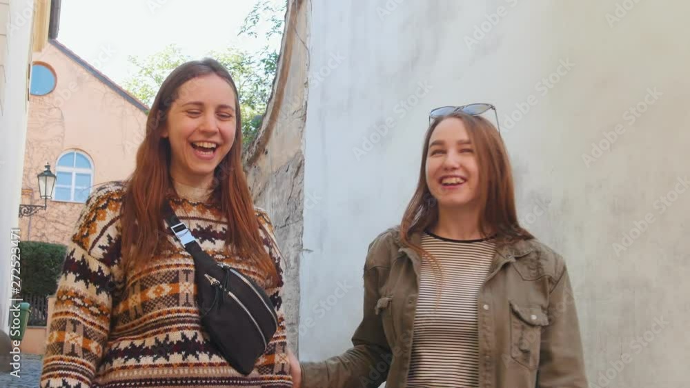 Two young women walking on the narrow streets. Talking and laughing Two young women walking on the narrow streets. Talking and laughing