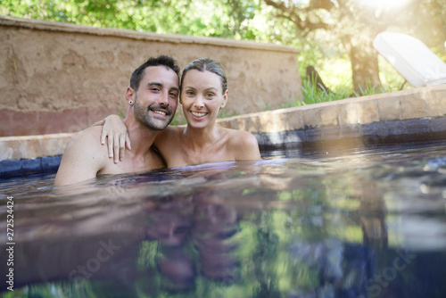Cheerful couple in Moroccan swimming pool smiling at camera