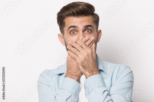 Horrified man covering mouth with hands looking at camera