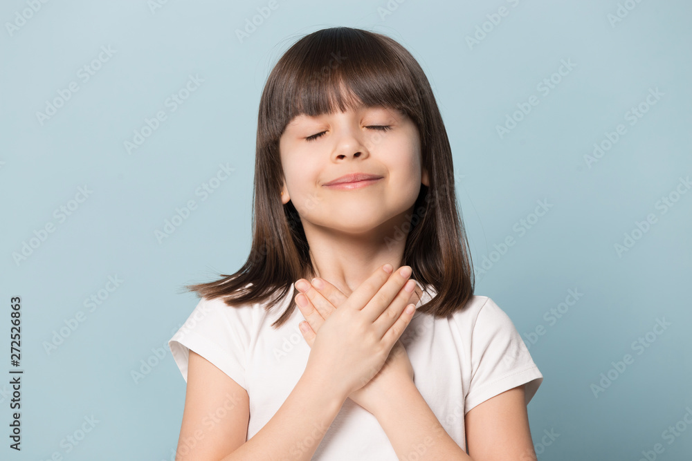Grateful little girl closed eyes hold hand on chest Grateful little girl closed eyes hold hand on chest