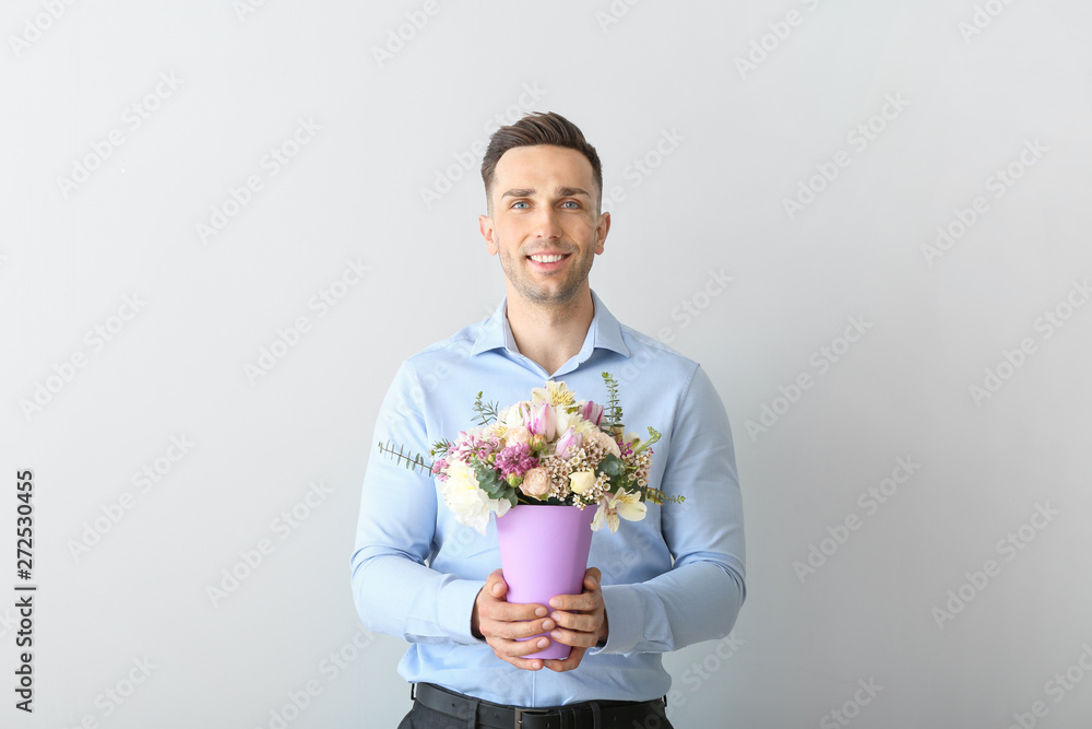 Handsome man with bouquet of beautiful flowers on light background Handsome man with bouquet of beautiful flowers on light background