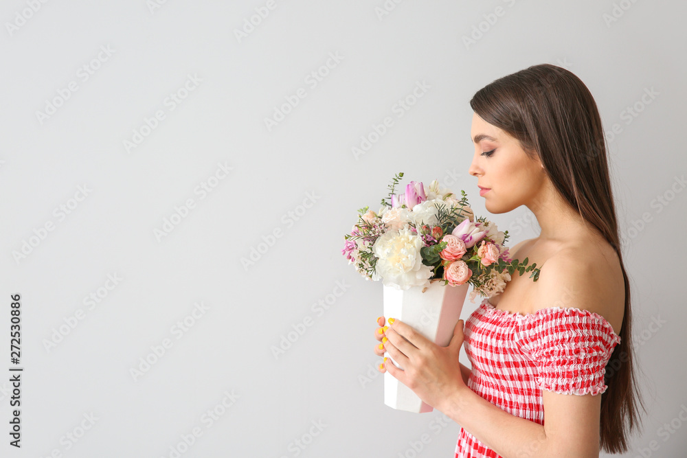 Beautiful young woman with bouquet of flowers on light background Beautiful young woman with bouquet of flowers on light background