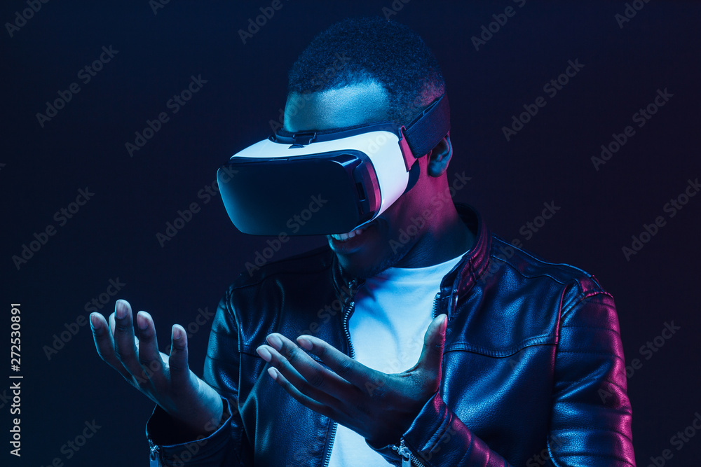 African man pictured in darkness feeling positive and enjoying opportunities of virtual reality