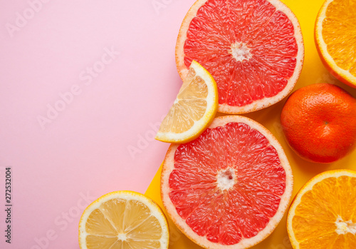 Flat lay of cut ripe juicy grapefruit, lemon and orange on pink background with copyspace.