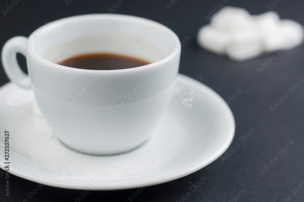 White coffee cup with sugar cubes isolated on a black background White coffee cup with sugar cubes isolated on a black background