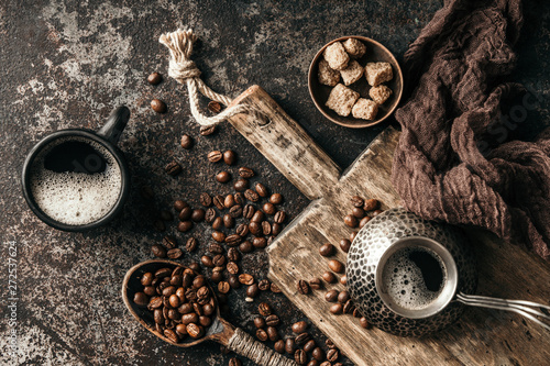 Coffee on wooden board with coffee beans on dark textured background. Top view with copy space. Background with free text space.