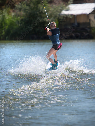 Fototapeta Naklejka Na Ścianę i Meble -  Young pretty slim woman riding wakeboard in summer