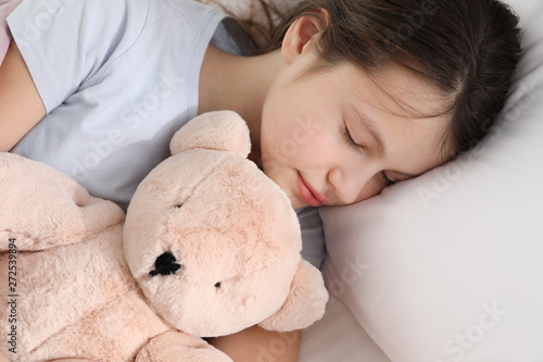 Beautiful little girl with teddy bear sleeping in bed