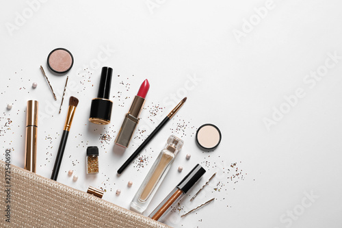 Cosmetic bag and different luxury makeup products on white background, top view