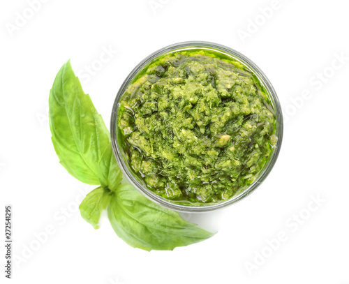 Bowl of tasty pesto sauce with basil leaves isolated on white, top view