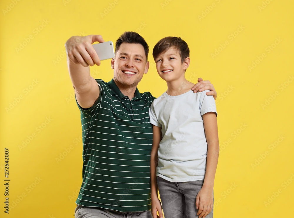 Dad and his son taking selfie on color background - obrazy, fototapety, plakaty 