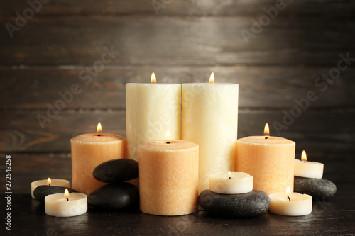 Beautiful composition with lit candles and spa stones on table