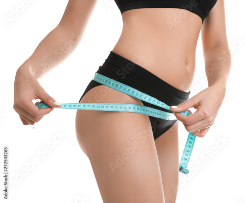 Slim young woman measuring her body with tape on white background, closeup