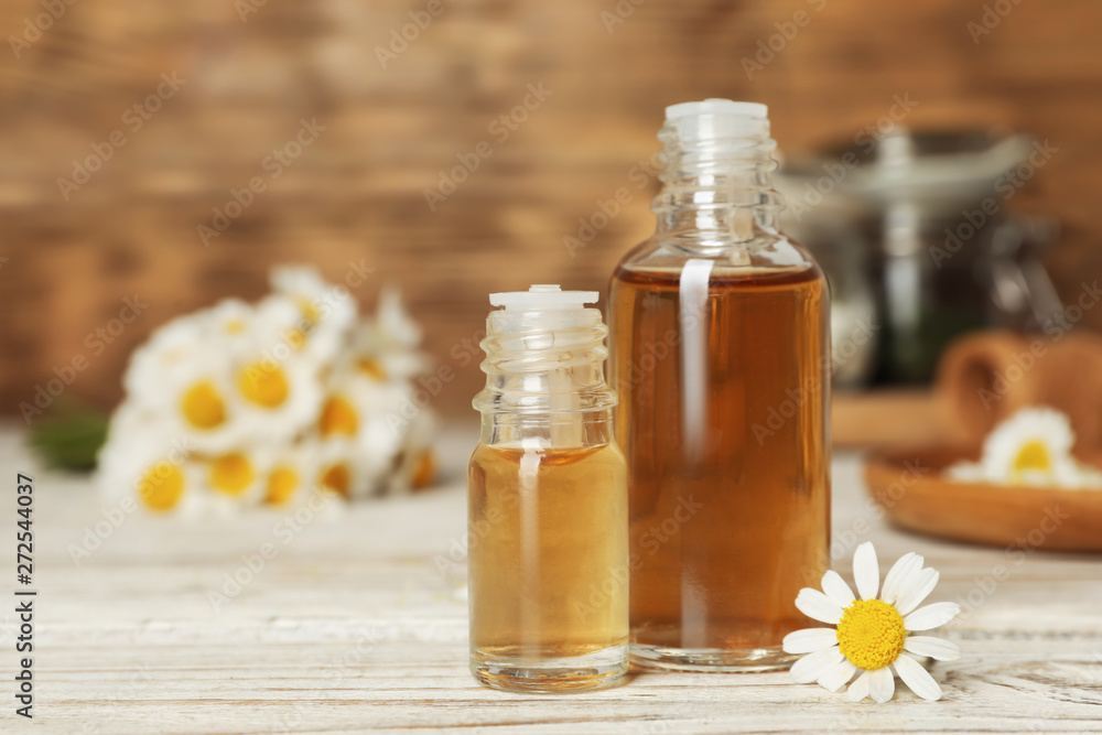 Composition with bottles of chamomile essential oil on table. Space for text Composition with bottles of chamomile essential oil on table. Space for text